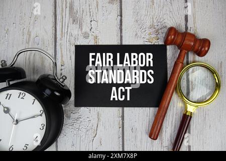 Fair Labor Standards Act Text auf Papierkarte mit Wecker und hölzernem Richter Gavel von oben auf hölzernem Hintergrund Stockfoto