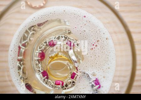 Reinigung Vintage Schmuck Diamant Ring und Armband in Glas auf Holztischhintergrund Stockfoto