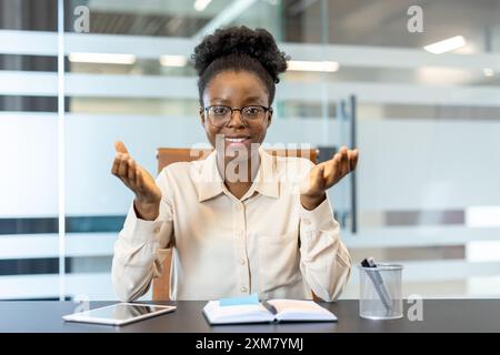 Selbstbewusste Geschäftsfrau im modernen Büro, die Videoanrufe führt. Sie erklärt Ideen und Strategien. Professionelles Setting mit Notebook und Tablet auf dem Schreibtisch. Ideal für Business und Kommunikation Stockfoto