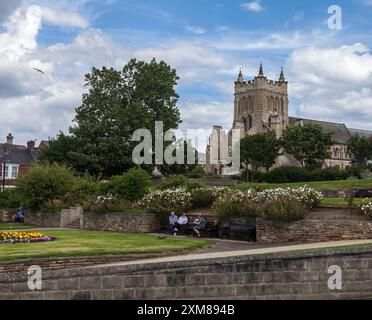 Eine malerische Gegend von Croft Gardens mit Leuten, die auf Bänken und St. saßen Hildas Church at the Headland, Old Hartlepool, England, Großbritannien im Hintergrund Stockfoto