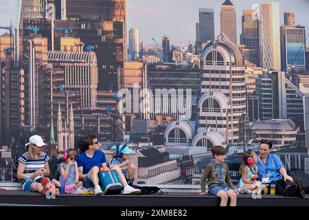 Vor einem Hintergrund mit einer Skyline von London sieht eine Familie eine Flugschau während der Farnborough International Airshow am 26. Juli 2024 in Farnborough, England. Die diesjährige, halbjährliche Farnborough International Airshow bietet 1.500 Aussteller mit 100 000 m2 Ausstellungsfläche und über 80.000 Besuchern an den 5 Tagen. Stockfoto