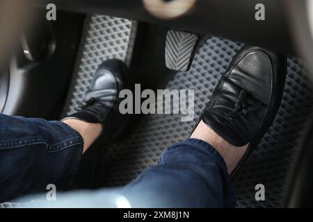 Mann in schwarzen Schuhen, der auf das Pedal der Autobremse drückt, Nahaufnahme Stockfoto