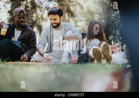 Multirassische Gruppe von Freunden, die an einem sonnigen Tag im Park eine Partie Backgammon genießen Stockfoto