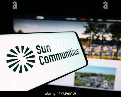 Mobiltelefon mit Logo des amerikanischen Immobilienunternehmens Sun Communities Inc. Vor der Website. Konzentrieren Sie sich auf die Mitte des Telefondisplays. Stockfoto