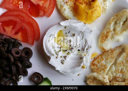 Ein typisch libanesischer Frühstücksteller mit Labneh, Spiegeleiern, gebackenem halloumi-Käse, Tomaten und Oliven. Stockfoto