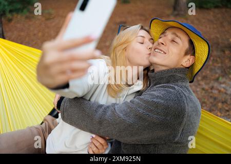 Verspielte Partner machen ein Selfie, während sie in einer Hängematte entspannen Stockfoto