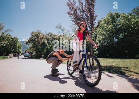 Freunde genießen einen sonnigen Tag mit Skateboard und Fahrrad in einem malerischen Park Stockfoto