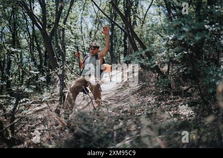Junger Mann, der an einem sonnigen Sommertag durch einen dichten Wald wandert und eine abenteuerliche Wanderung genießt Stockfoto