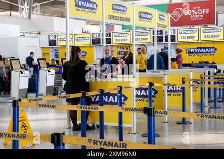 Die Mitarbeiter von Ryanair stehen am Check-in-Schalter von Ryanair am Flughafen London Stansted zur Verfügung. Der London Stansted Airport ist ein internationaler Flughafen, der etwa 30 Meilen nördlich von Central London liegt. Es ist einer der großen Flughäfen, die London ansteuern. Stockfoto