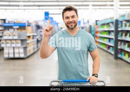 Mann mit Einkaufswagen. Idee anzeigen. Impulskäufe. Zufallskauf. Einkäufe von Menschen ohne einen bestimmten Plan oder eine bestimmte Absicht, oft getrieben von b Stockfoto