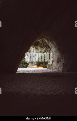 Blick von einer dunklen Höhle auf einen Strand mit Bäumen und Felsen, Cape Reinga, Neuseeland Stockfoto