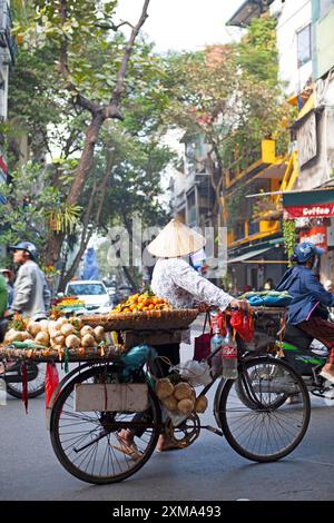 Vietnamesischer Straßenverkäufer mit konischem Hut und Fahrrad in der Altstadt von Hanoi, Vietnam Stockfoto