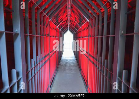 Ein langer Tunnel mit roter Beleuchtung und metallischen Strukturen vermittelt eine futuristische und industrielle Atmosphäre, Landschaftspark Duisburg Nord, Meiderich Stockfoto