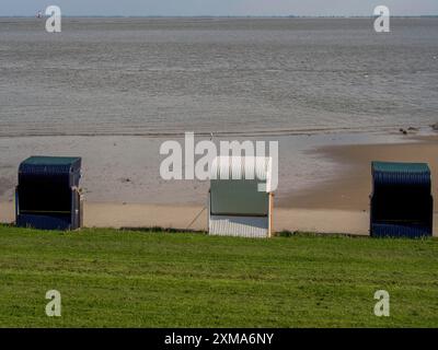 Drei Liegestühle am Strand mit herrlichem Blick auf das weite ruhige Meer und den klaren Himmel, wilhelmshaven, deutschland Stockfoto