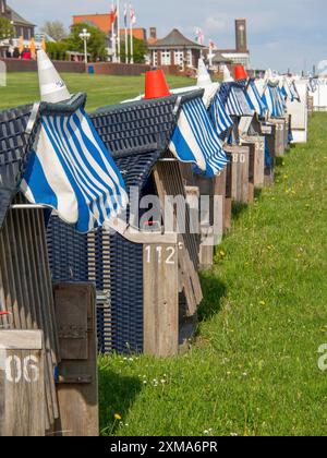 Liegestühle mit nummerierten Holzbänken und blau-weißen Bezügen auf einer Wiese nahe der Promenade, wilhelmshaven, deutschland Stockfoto