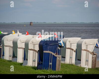 Mehrere Liegestühle stehen an der Küste vor einer Wiese, mit Meer und Himmel im Hintergrund, wilhelmshaven, deutschland Stockfoto