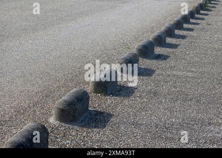 Eine Reihe von runden Betonpfollern am Straßenrand erzeugt ein Muster aus Schatten und Licht Stockfoto