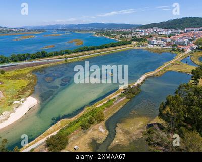 Panoramablick auf eine Wasserlandschaft mit Flusslauf, Straßen und einer kleinen Stadt umgeben von Hügeln und Natur, aus der Vogelperspektive, Fluss Lima, Viana Do Stockfoto