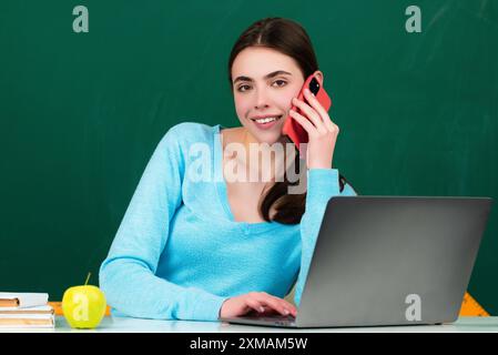 Schülerin, die im Klassenzimmer telefoniert. Schulmädchen chtigt auf dem Handy in der Nähe der Tafel. College Student lernen im College Klassenzimmer. Bildungswesen Stockfoto