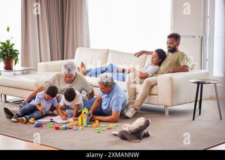 Große Familie, Kinder und spielen mit Großeltern, zu Hause und Spielzeug mit Kreativität, Spaß und Spielen. Freizeit, Freude und Leute im Wohnzimmer, Ausmalen Stockfoto