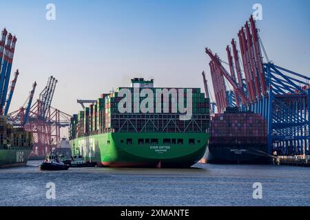 Containerschiff, das jemals begabt ist und im Hamburger Hafen, Waltershofer Hafen, HHLA Containerterminal Burchardkai ankommt, manövrieren 4 Hafenschlepper die Stockfoto