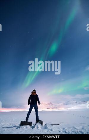 Einsamer Wanderer, der die Polarlichter der Aurora Borealis bestaunt, in Island, Fernweh, Touristen, Abenteuerlust Stockfoto