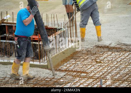 Baustelle, Betonierung, die Bodenplatte eines Gebäudes wird betoniert, der Beton wird auf die Stahlbetonmatten gepumpt, wodurch das verteilt wird Stockfoto