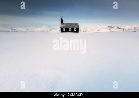 Schwarze Kirche von Budir in Island, Winterzeit minimalistisch, christentum, sonniger Tag, Berge im Hintergrund Stockfoto