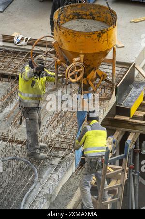 Baustelle, Betonieren, die Decke eines Gebäudes wird betoniert, der Beton wird mit einer Betonbombe auf die Stahlbetonmatten gelegt Stockfoto