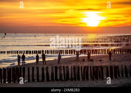 Sonnenuntergang am Strand von Zoutelande, Strand mit Holzpfahlbrüchen, Zeeland, Niederlande Stockfoto