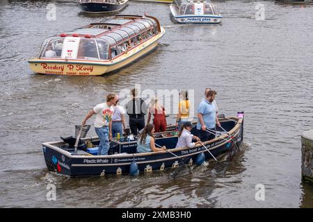 Plastikwalboot in einem Kanal in Amsterdam, Passagiere fischen Plastikmüll aus den Kanälen, fahren durch die Kanäle von Amsterdam, sammeln Abfall Stockfoto