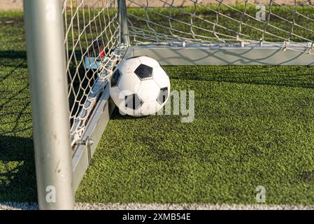 Ein schwarz-weißer Fußball, der durch einen kräftigen Schuss angetrieben wird und das Netz durchbricht, um ein perfektes Tor zu erzielen. Das wulstige Netz betont den Aufprall und die Qualität Stockfoto