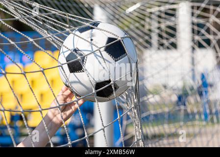 Ein schwarz-weißer Fußball, der durch einen kräftigen Schuss angetrieben wird und das Netz durchbricht, um ein perfektes Tor zu erzielen. Das wulstige Netz betont den Aufprall und die Qualität Stockfoto