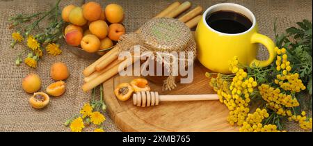 Sommerstillleben mit Kaffee, Honig, Aprikosen und gelben Blumen Stockfoto