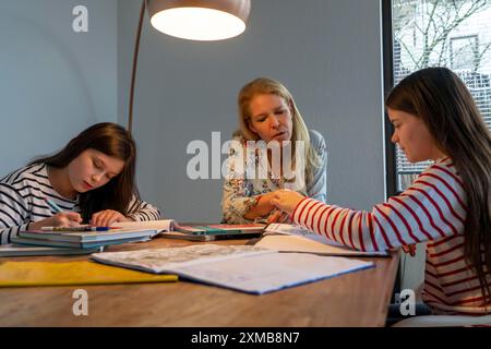 Während der Abriegelung im Januar 2021 hilft die Mutter ihren beiden Töchtern zu Hause, zu lernen, Schulschließungen, Fernunterricht, Auswirkungen von Stockfoto
