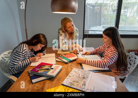 Während der Abriegelung im Januar 2021 hilft die Mutter ihren beiden Töchtern zu Hause, zu lernen, Schulschließungen, Fernunterricht, Auswirkungen von Stockfoto