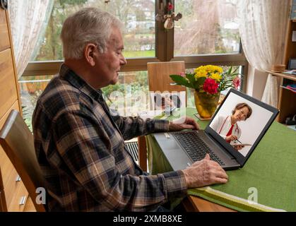 Symbolisches Bild der Telemedizin, älterer Patient, der in einer Videokonferenz von zu Hause aus mit einem Arzt spricht Stockfoto