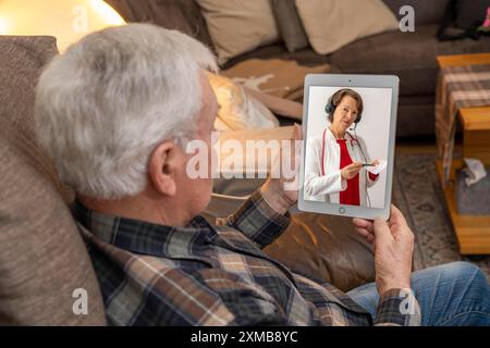 Symbolisches Bild der Telemedizin, älterer Patient, der in einer Videokonferenz von zu Hause aus mit einem Arzt spricht Stockfoto