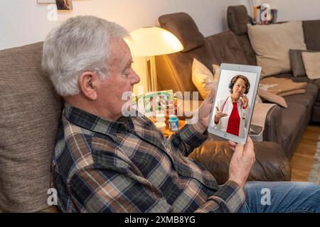 Symbolisches Bild der Telemedizin, älterer Patient, der in einer Videokonferenz von zu Hause aus mit einem Arzt spricht Stockfoto