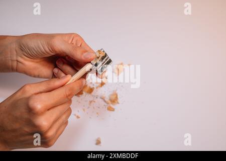 Eine Person benutzt eine hölzerne Zahnbürste, um einen Bleistift zu schärfen. Konzept von Einfachheit und Einfallsreichtum, da die Person ein natürliches Material verwendet, um zu scha Stockfoto