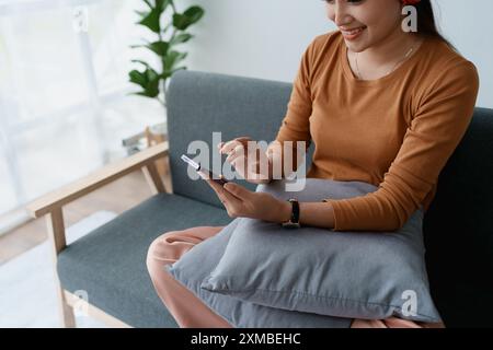 Eine Frau fühlt sich völlig entspannt, während sie mit ihren Kopfhörern sitzt und Musik auf ihrem Smartphone hört. Stockfoto