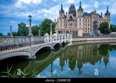 Schwerin, Deutschland. Juli 2024. Das Schweriner Schloss spiegelt sich im Wasser des Burgsees. Am 27. Juli 2027 soll in Neu-Delhi (Indien) beschlossen werden, das Schweriner Wohnensemble in die begehrte UNESCO-Welterbeliste aufzunehmen. Schwerin hofft, dass seine Aufnahme in das UNESCO-Weltkulturerbe den Tourismus ankurbeln und mehr internationale Aufmerksamkeit erregen wird. Quelle: Jens Büttner/dpa/Alamy Live News Stockfoto