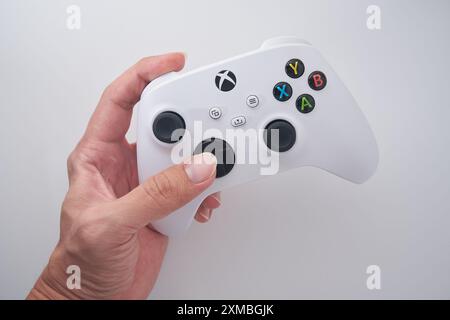 Ein Mann hält einen XBOX-Controller mit weißem Hintergrund. Stockfoto