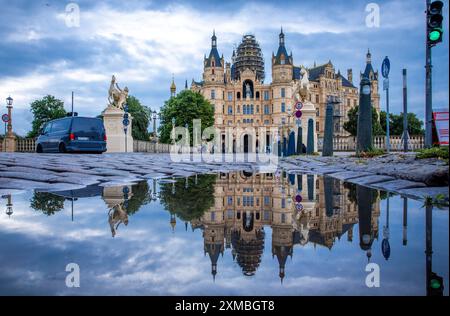 Schwerin, Deutschland. Juli 2024. Schloss Schwerin spiegelt sich in einer Pfütze. Am 27. Juli 2027 soll in Neu-Delhi (Indien) beschlossen werden, das Schwerin Residence Ensemble in die begehrte UNESCO-Liste des Weltkulturerbes aufzunehmen. Schwerin hofft, dass seine Aufnahme in das UNESCO-Weltkulturerbe den Tourismus ankurbeln und mehr internationale Aufmerksamkeit erregen wird. Quelle: Jens Büttner/dpa/Alamy Live News Stockfoto