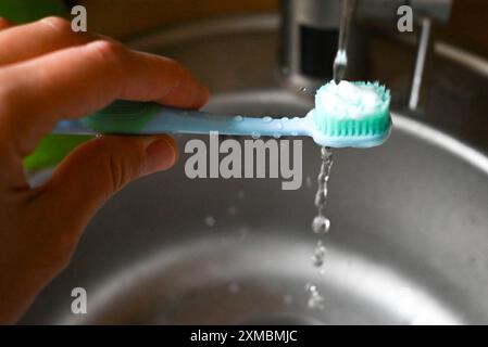 Eine Zahnbürste mit weißen Borsten wird in der Hand gehalten Stockfoto