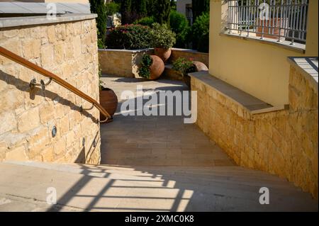 Eine Steintreppe führt zu einem wunderschönen üppigen Garten mit Blumen und großen Gläsern. Das luxuriöse Aphrodite Hills Hotel und Resort Gebäude mit wunderschönen Stockfoto