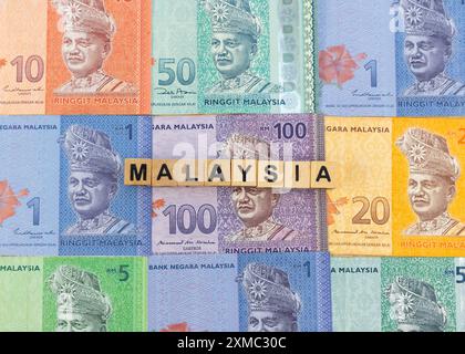 Tuanku Abdul Rahman Porträt auf malaysischen Ringgit-Banknoten. Malaysia Wort auf Holzblöcken Würfel über Banknoten. Stockfoto