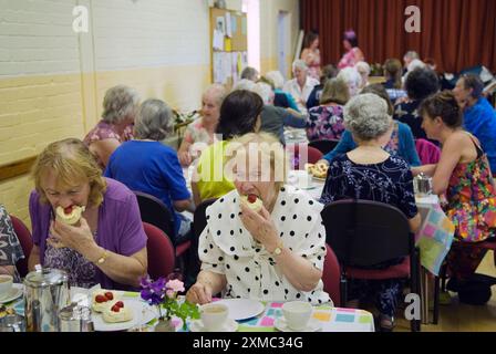 Village Hall, Cream Tea. The Nether Stowey Female Friendly Society; The Womens Walk on Club Day. Am Ende der Nachmittagsfeier gab es einen Creme-Tee, der 2014 5,00 Pfund kostete. Zwei Frauen essen Erdbeercremebrötchen. Nether Stowey, Somerset, England 21. Juni, UK 2010s HOMER SYKES Stockfoto