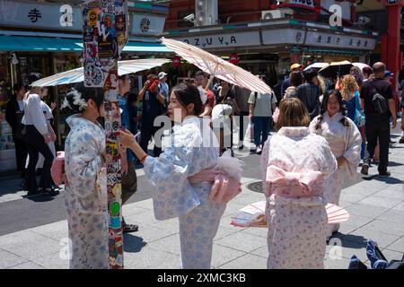 Tokio, Japan - 15. Juni 2024: Frauen tragen Kimonos, während sie Nakamise besuchen, die berühmteste Einkaufsstraße in Asakusa in der Nähe des Senso-Ji-Tempels, Tokio's Stockfoto