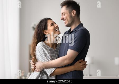Wunderschönes tausendjähriges Liebespaar, das sich umarmt und zusammen im Wohnzimmer steht Stockfoto